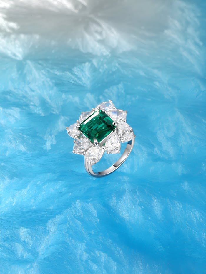 Stunning emerald-cut ring with diamond accents set against a vibrant blue background.